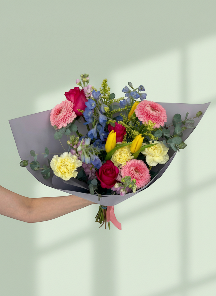 Lakewood Florist Cut Confetti Bouquet: Pink gerberas, yellow tulips, red roses, yellow carnations, blue delphiniums, and eucalyptus.
